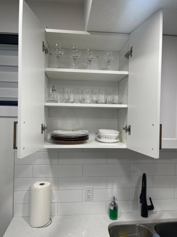 a kitchen with white cabinets with plates and glasses at Stylish 2 Bedroom suite in SW Edmonton close to Windermere and Edmonton International Airport in Edmonton