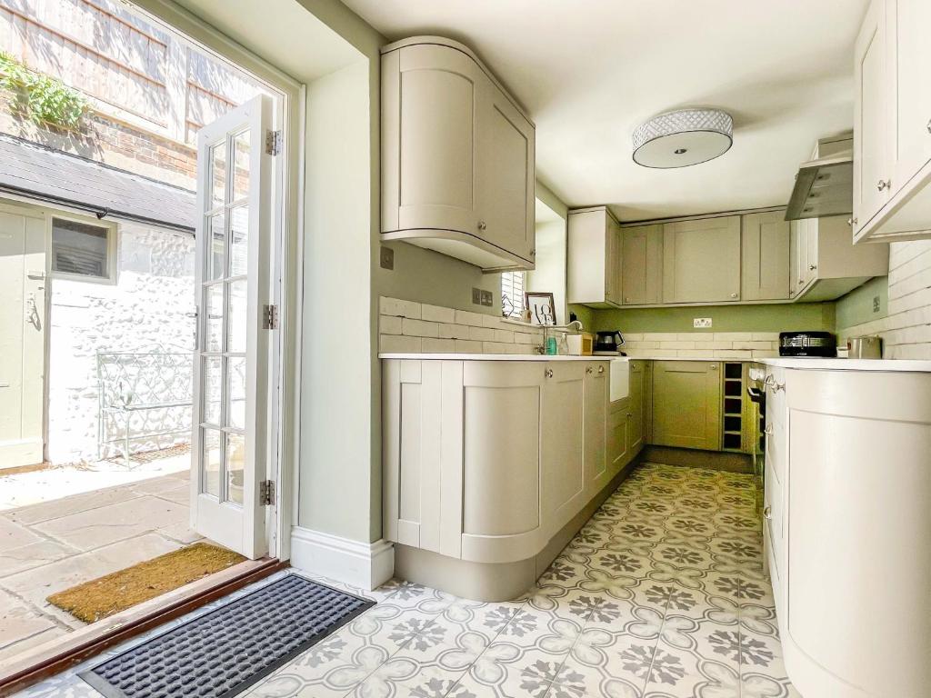 a kitchen with green walls and white cabinets at Beautiful 2 Bedroom Cottage with Private Courtyard in Arundel Centre in Arundel