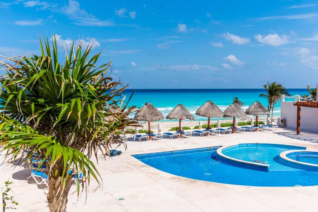 una piscina del complejo con sillas y sombrillas y el océano en Lindo loft en playa Marlin, 2 min de Plaza la Isla - Mar310 - en Cancún