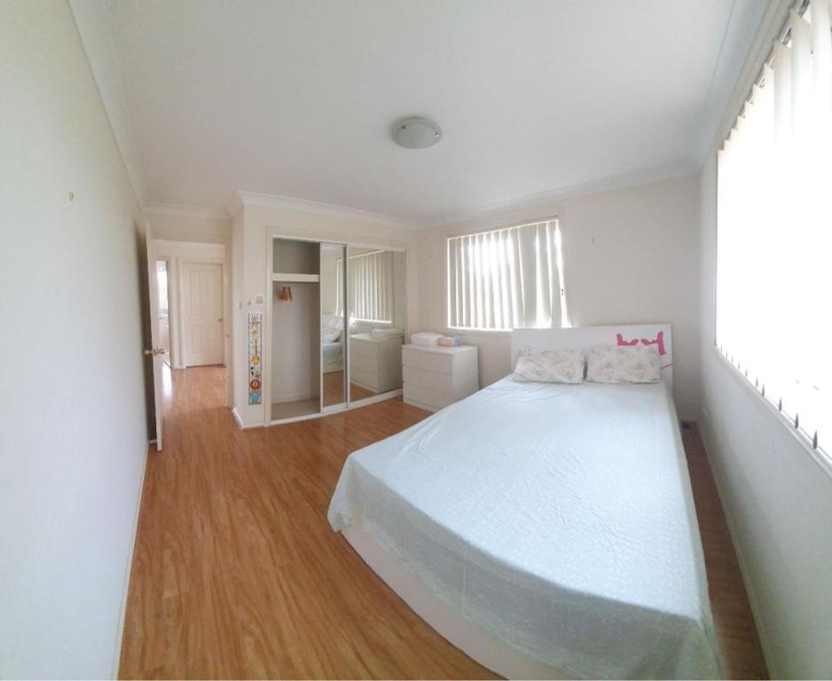 a white bedroom with a large bed and a bathroom at A cosy private bedroom for you (2) in Warwick Farm