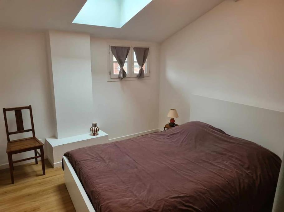 ein Schlafzimmer mit einem Bett, einem Stuhl und einem Fenster in der Unterkunft Maison de village du 18ème Drôme des Collines in Les Veyrières