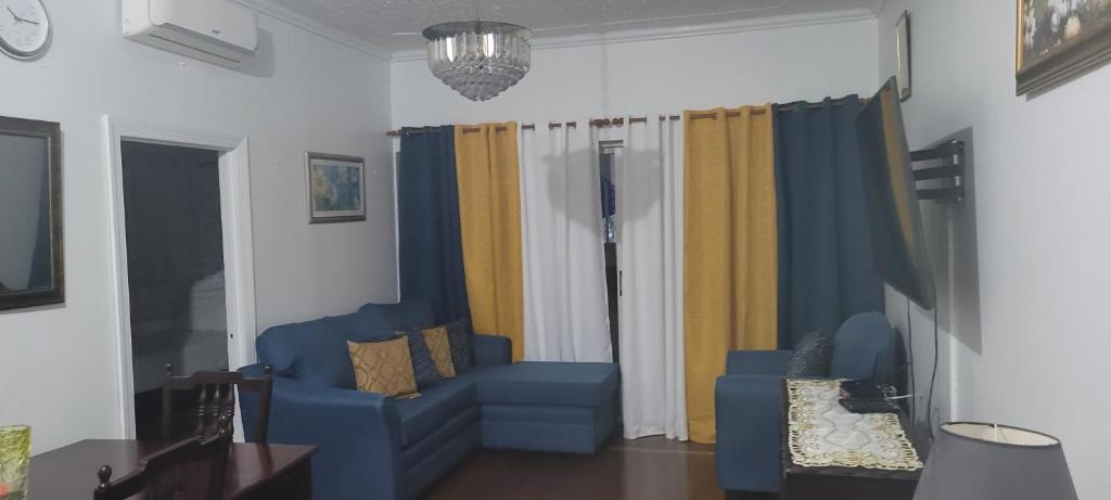 a living room with a blue couch and curtains at The Braemar Suite III New Kingston in Kingston