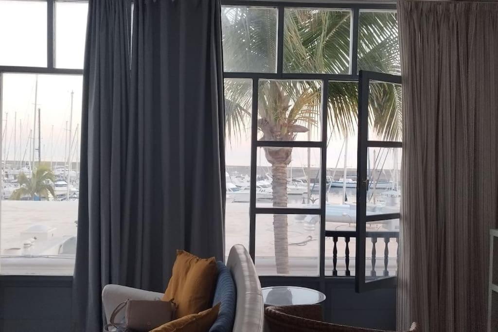 a living room with a palm tree outside a window at Casa marea in Puerto Calero