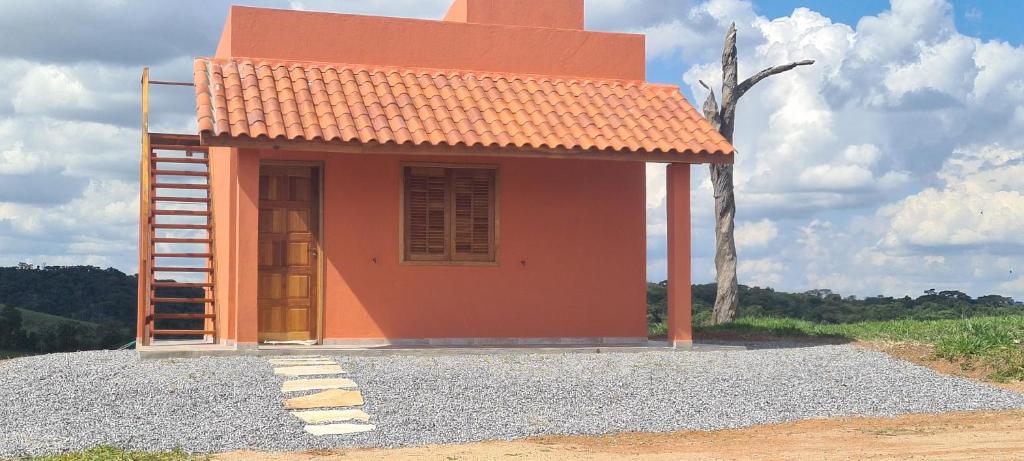 uma pequena casa com um telhado laranja em cima de cascalho em Pousada Colina das Maritacas em São Tomé das Letras