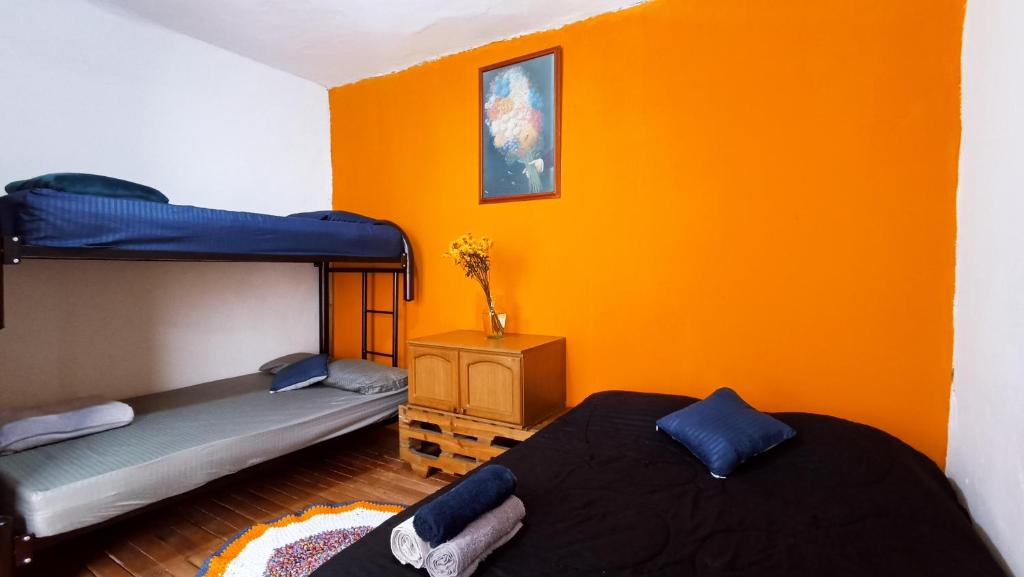 two beds in a room with an orange wall at Mico Loco Casa Hostal in Bogotá