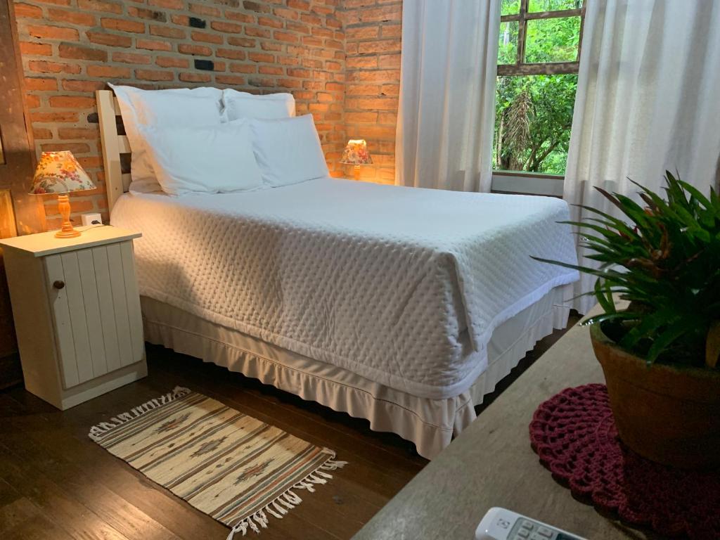ein Schlafzimmer mit einem Bett und einer Ziegelwand in der Unterkunft Casa ecológica na Montanha in Praia Grande