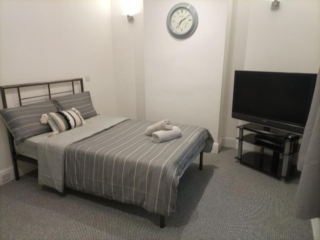 a bedroom with a bed and a clock on the wall at Large 'n' bright House in Middlesbrough