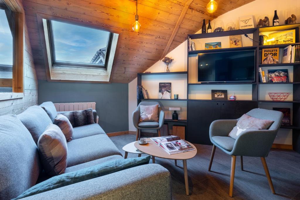 un salon avec un canapé, des chaises et une télévision dans l'établissement Duplex tout confort au centre-ville de Chamonix, à Chamonix-Mont-Blanc