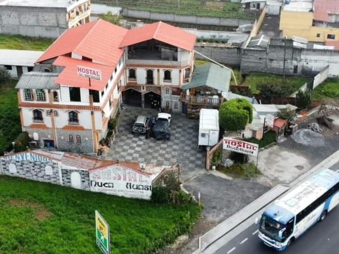 ein großes Haus mit einem Bus davor geparkt in der Unterkunft Hostal Ñuca Huasi in Tambillo