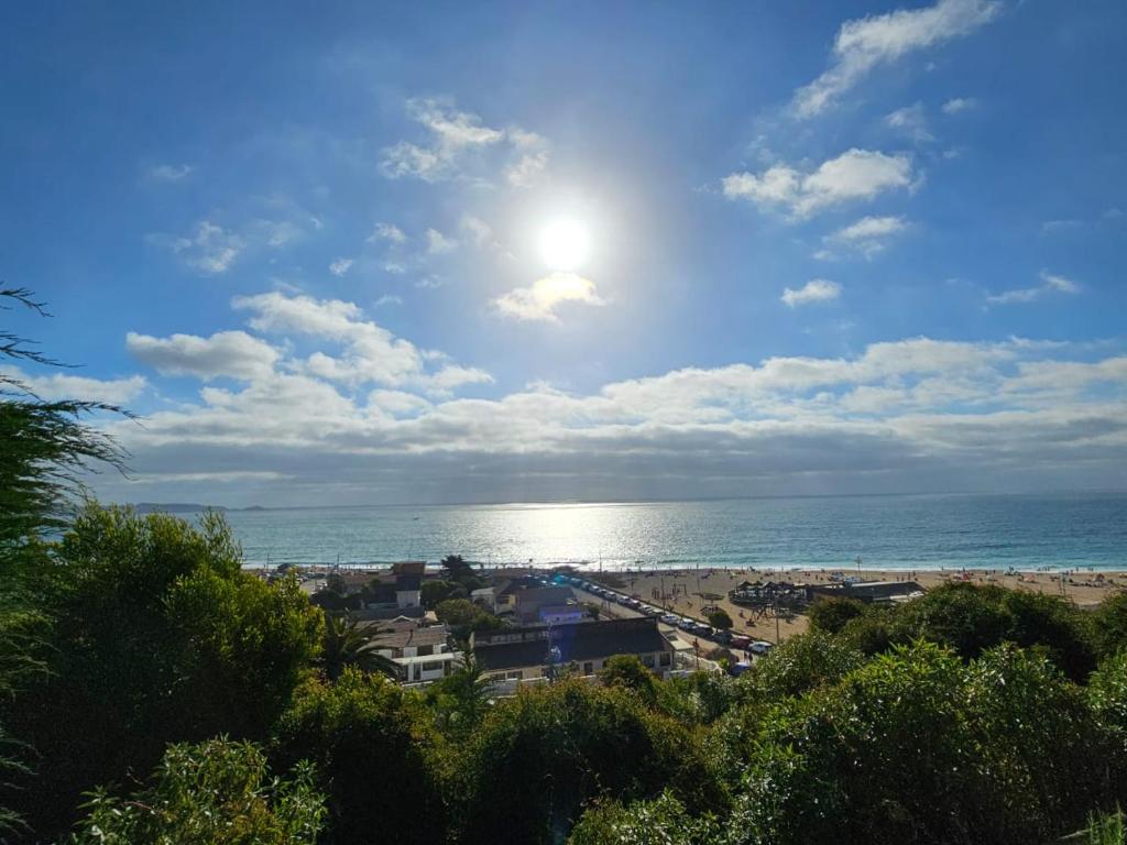 een uitzicht op een strand met de zon en de oceaan bij Cabaña Vista Bahia Algarrobo in Algarrobo