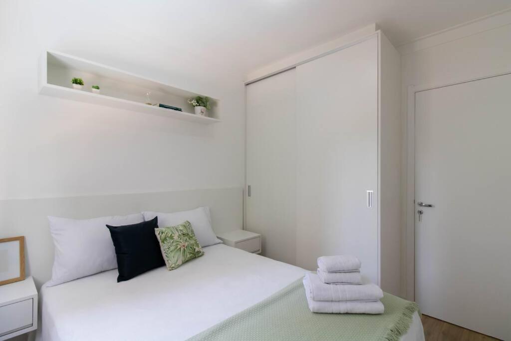 een witte slaapkamer met een bed met handdoeken erop bij Just Vero Apartament - GRU in Guarulhos