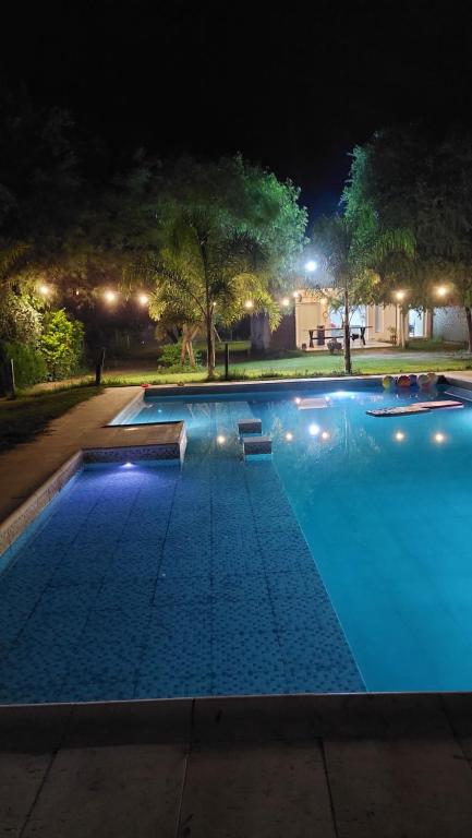 una gran piscina por la noche con luces en Camino Marquez en Santiago del Estero