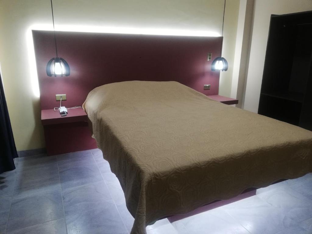 Hostal sublime في كوتشابامبا: غرفة نوم مع سرير وطاولتين مع أضواء