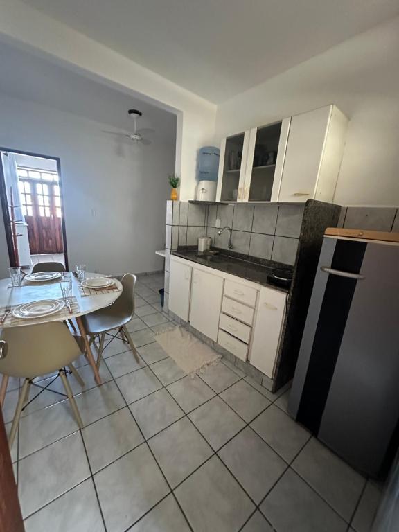 cocina con armarios blancos, mesa y sillas en Apartamento com varanda, en Mucuri