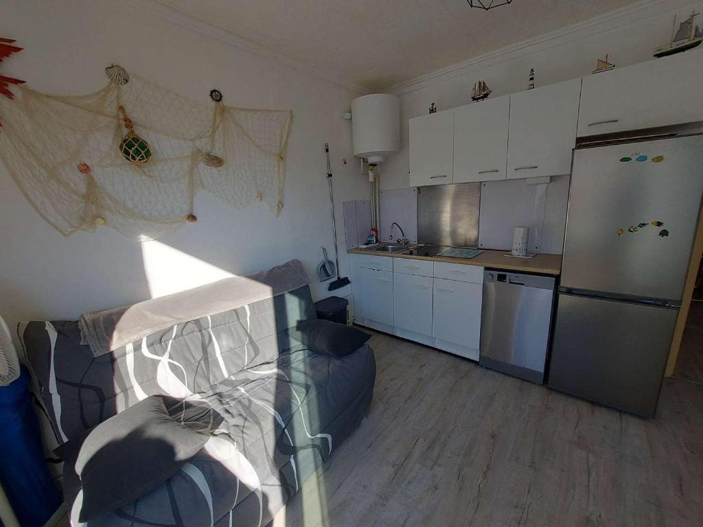 Il comprend une petite cuisine avec un canapé et un réfrigérateur. dans l'établissement Appartement T2 à Marseillan Plage : terrasse, jardin, parking, proche plage et commerces - FR-1-326-796, à Marseillan