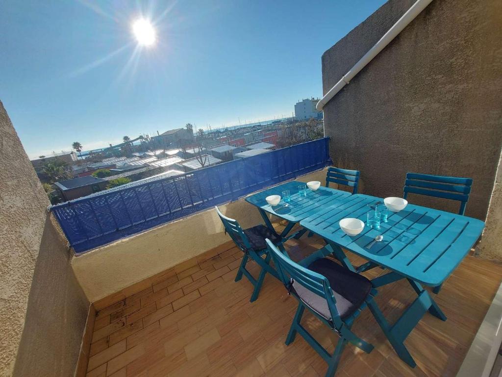 une table bleue et des chaises sur un balcon dans l'établissement Appartement 2P avec Terrasse Sud, Parking, WIFI et Animaux Acceptés à Marseillan - FR-1-326-797, à Marseillan