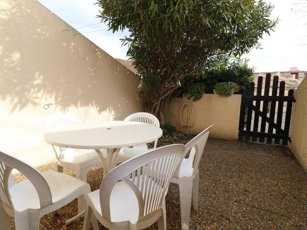 une table et des chaises blanches, une table et un arbre dans l'établissement Maison de Vacances P3, 5 Couchages, Climatisée, Terrasse ensoleillée, Parking privé, Proche Plage et Commerces - FR-1-307-248, au Grau-du-Roi