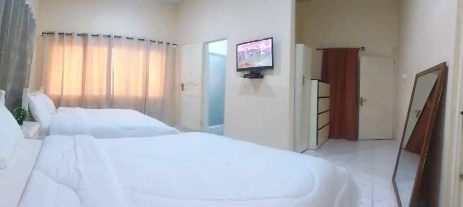 a white bedroom with a large bed and a television at Marrets International Villa in Accra