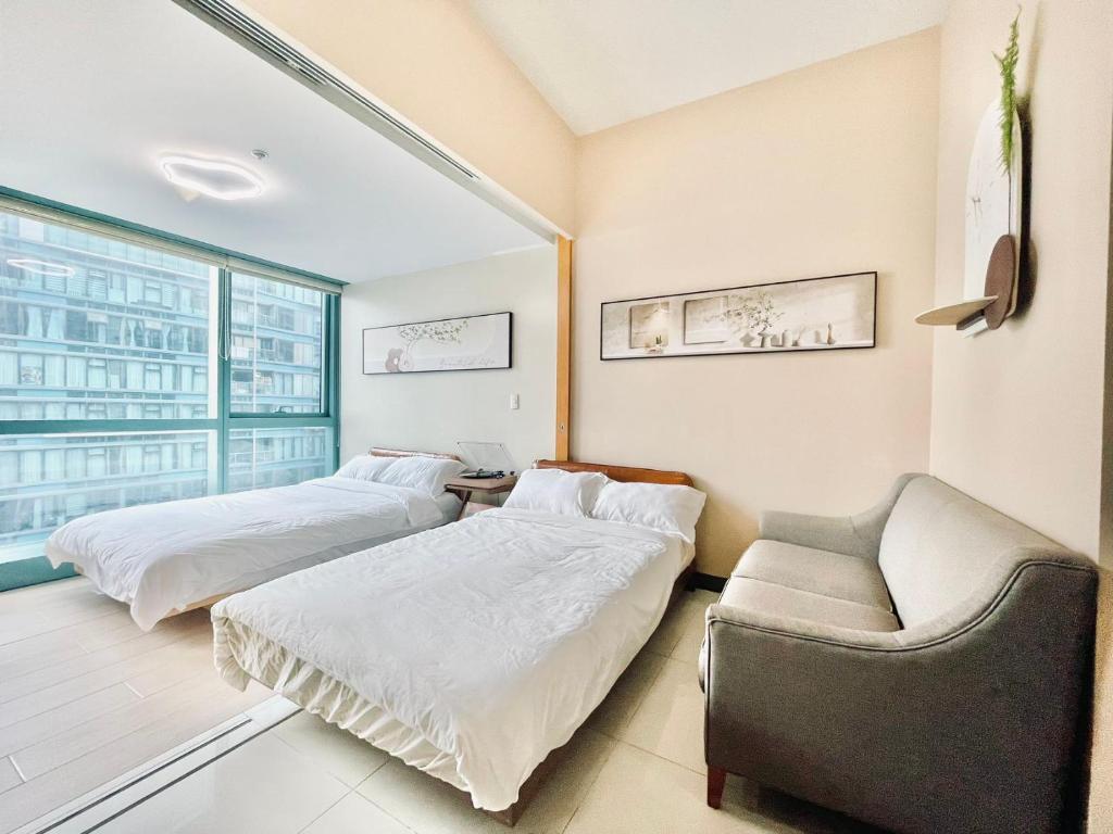 1 Schlafzimmer mit 2 Betten, einem Sofa und einem Fenster in der Unterkunft Thompson Suites - 2-beds, One Uptown Residences, 30F - XBOX & Netflix in Manila