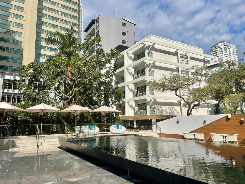 une piscine d'eau avec des parasols dans une ville dans l'établissement Floral Court Hotel & Residence Sukhumvit 13, à Bangkok