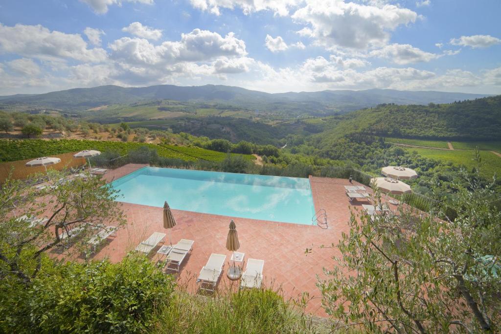 a large swimming pool with chairs and umbrellas at Castello Vicchiomaggio in Greve in Chianti