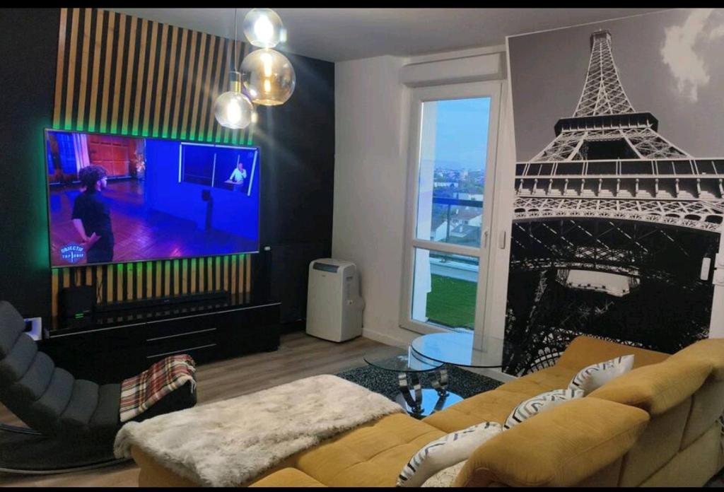 sala de estar con sofá y TV con la torre Eiffel en Superbe appartement en Gagny
