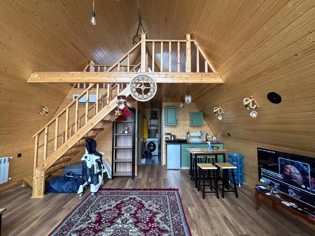 ein Wohnzimmer und eine Küche mit einer Treppe in einer Hütte in der Unterkunft A Frame Lankaran in Länkäran