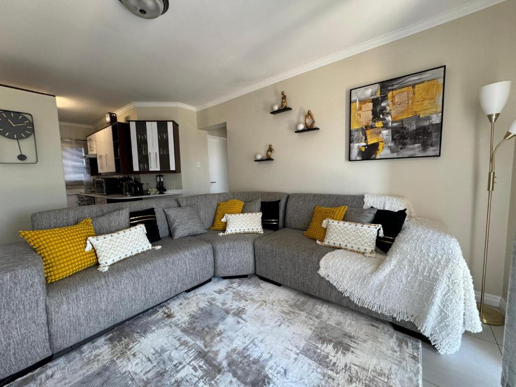金伯利的住宿－The Palms Unit 5，客厅配有灰色的沙发和黄色的枕头。
