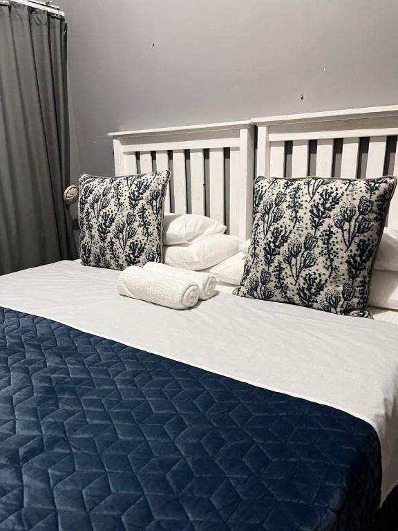 Cama con sábanas y almohadas azules y blancas en Lavender Lodge, en Mthatha