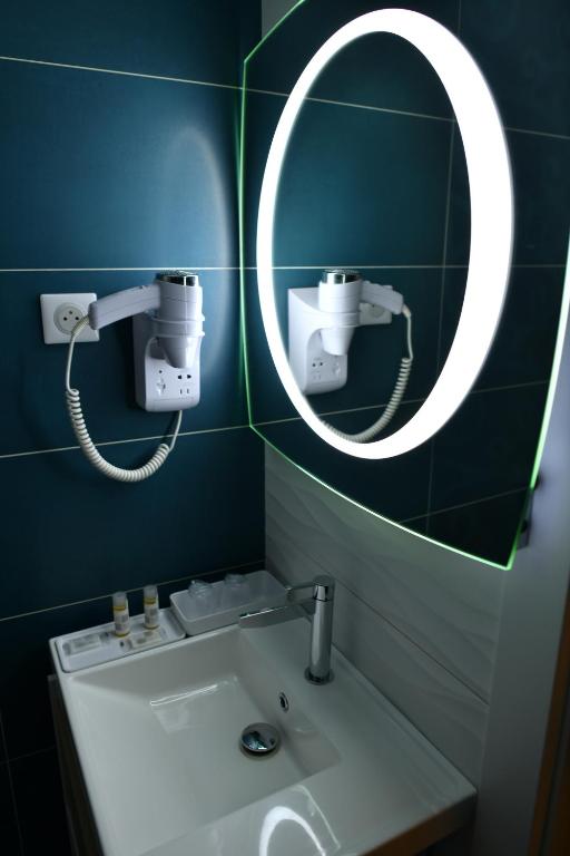 a bathroom with a mirror and a sink at Hôtel Le Claridge in Propriano