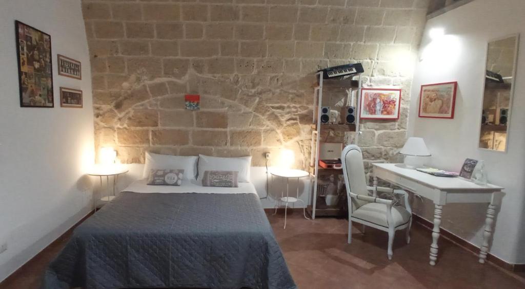 a bedroom with a bed and a desk in a room at Palazzo Saraceno apartments-Antico Rifugio in Taranto