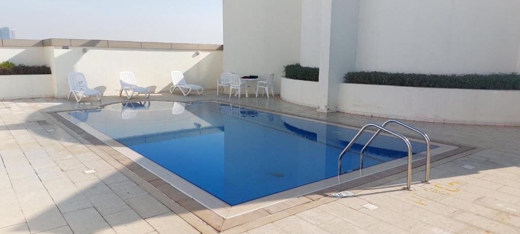 BEAUTIFUL VACATION HOME AT DUBAI BY MAUON TOURISM في دبي: مسبح وكراسي وطاولة في مبنى