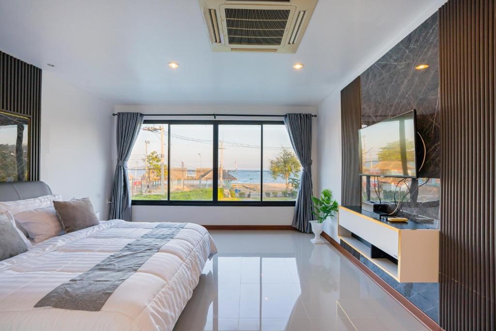 ein Schlafzimmer mit einem großen Bett und großen Fenstern in der Unterkunft Anda Sea View Pranburi in Ban Pak Nam Pran