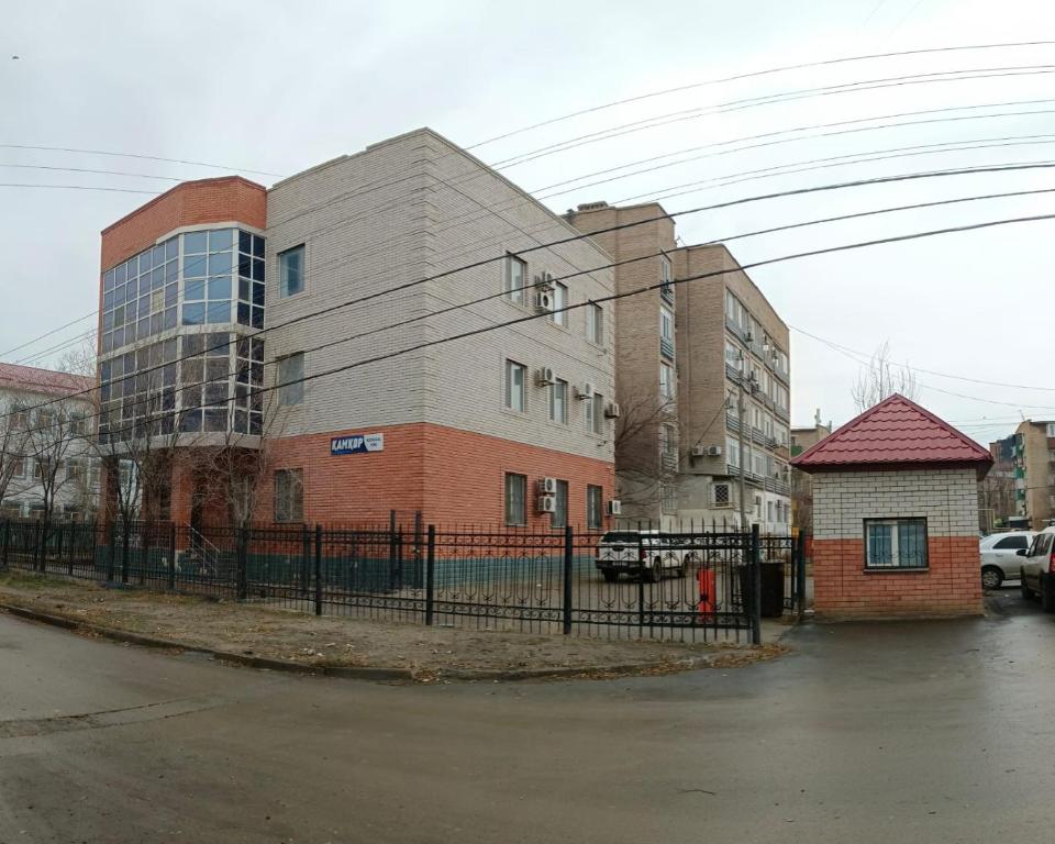 a building with a fence in front of a street at Kamkor in Atyrau