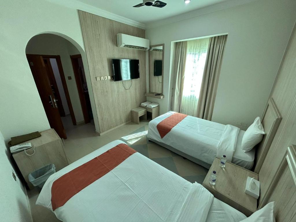 a hotel room with two beds and a mirror at Safari Hotel in Nizwa