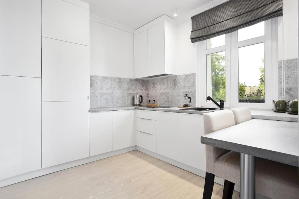 a white kitchen with white cabinets and a window at Pegaz 4 in Sopot