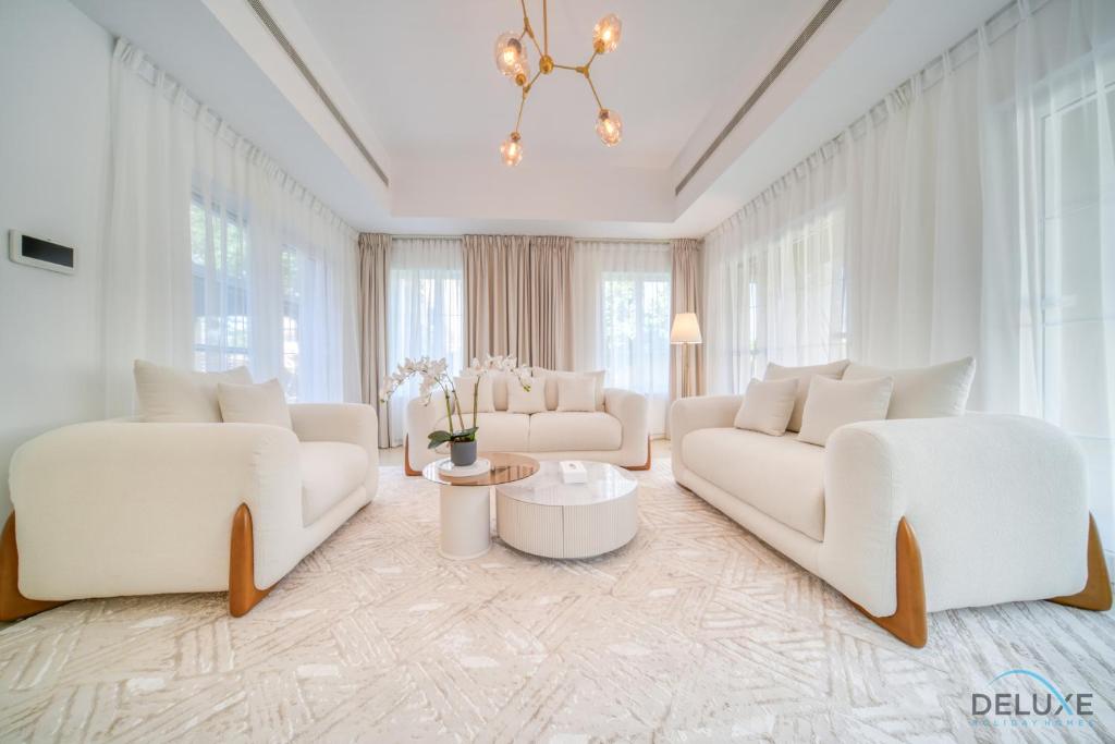 una sala de estar con muebles blancos y ventanas grandes. en Luxury 3BR Villa with Assistant Room at Alvorada 4 Arabian Ranches by Deluxe Holiday Homes, en Dubái