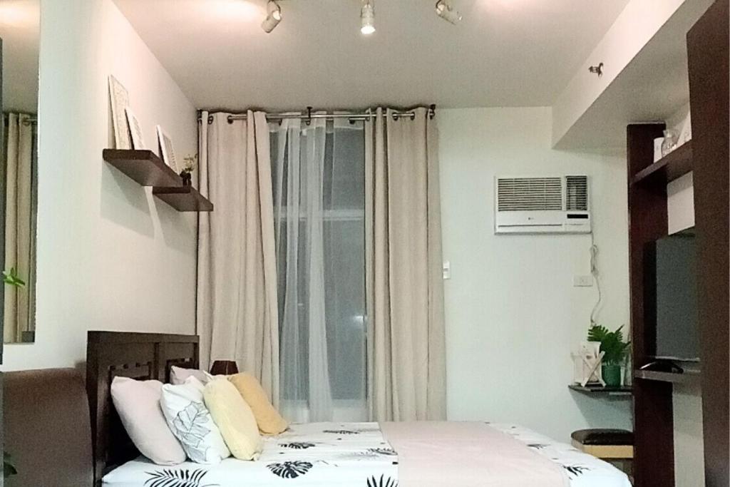 a bedroom with a bed and a window at Fully-furnished Condo Accommodation in Makati in Manila