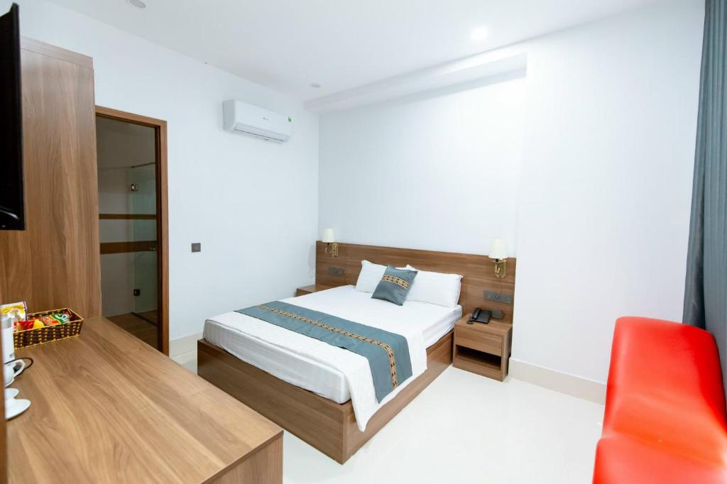a bedroom with a bed and a red chair at Khách sạn Vạn Phúc - Yên Bái in Xóm Soi (2)