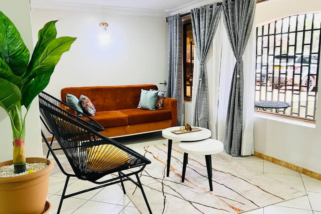 uma sala de estar com um sofá e uma mesa em Cozy Living by Miranda, Acacia - 2 BDR, 4 beds, 3 Bthrms, Unlimited WIFI, Free Parking, Netflix em Kampala