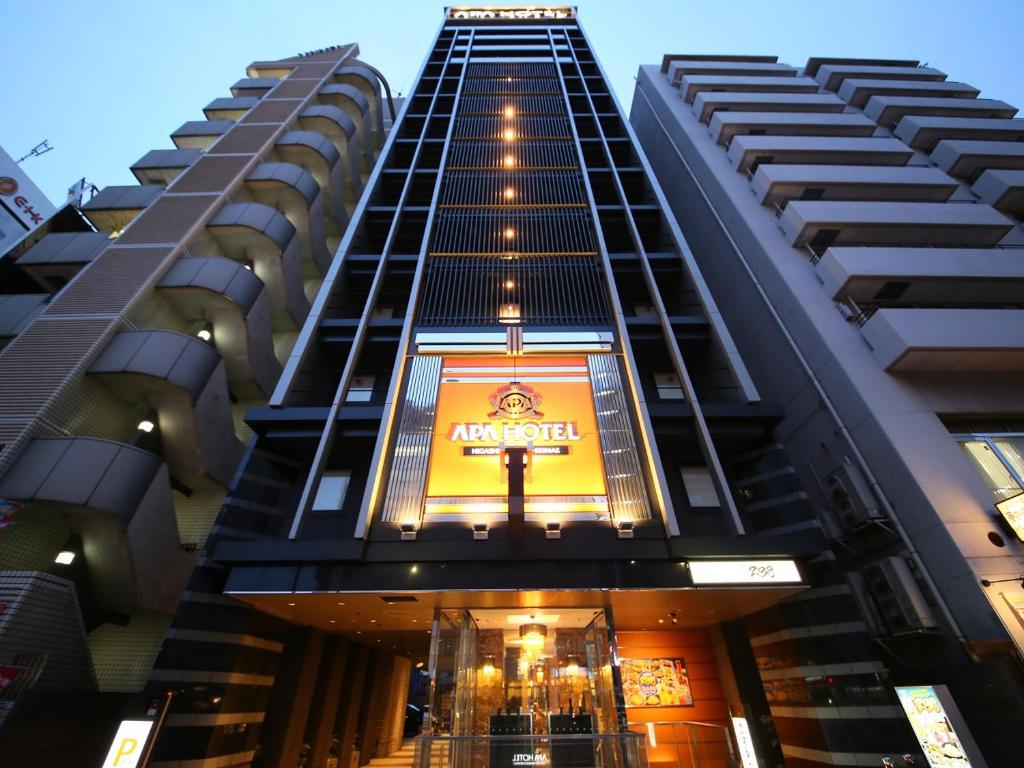 un grand bâtiment avec un panneau sur son côté dans l'établissement APA Hotel Higashi-Shinjuku-Ekimae, à Tokyo