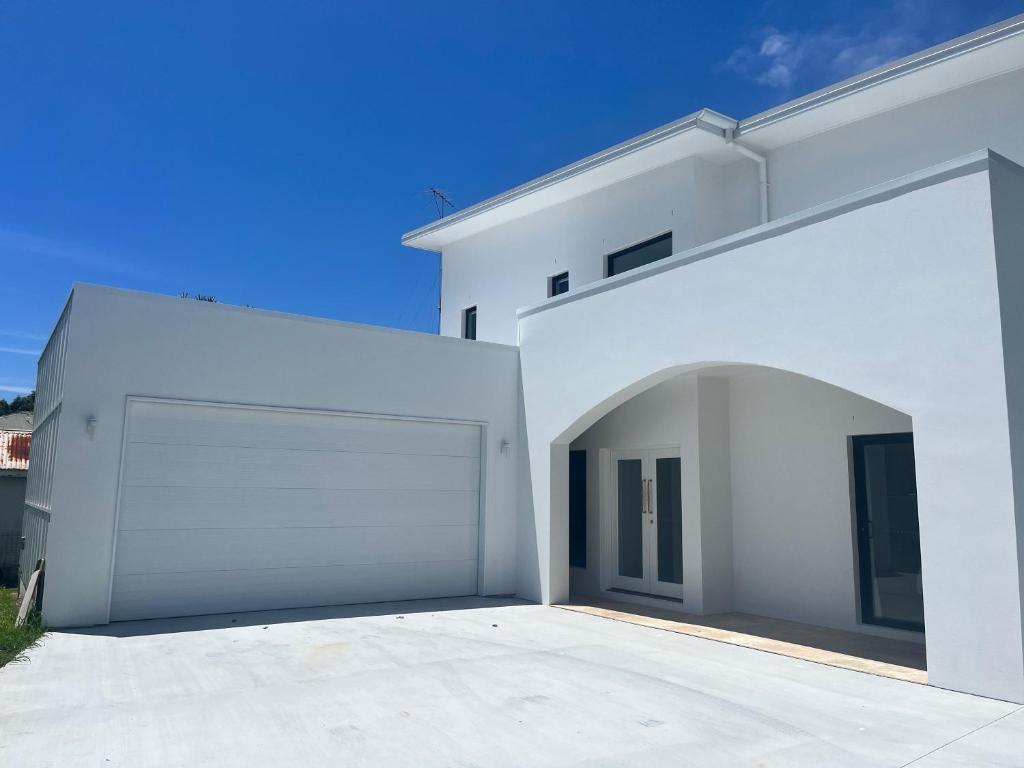 a white building with a large garage at The_Kennedy_house in Bilinga