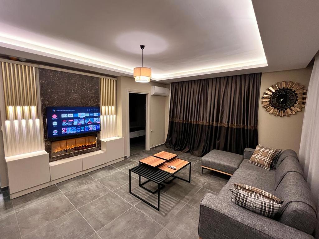 a living room with a couch and a tv at LİMONOTTO SUİT OTEL in Çiftlikköy