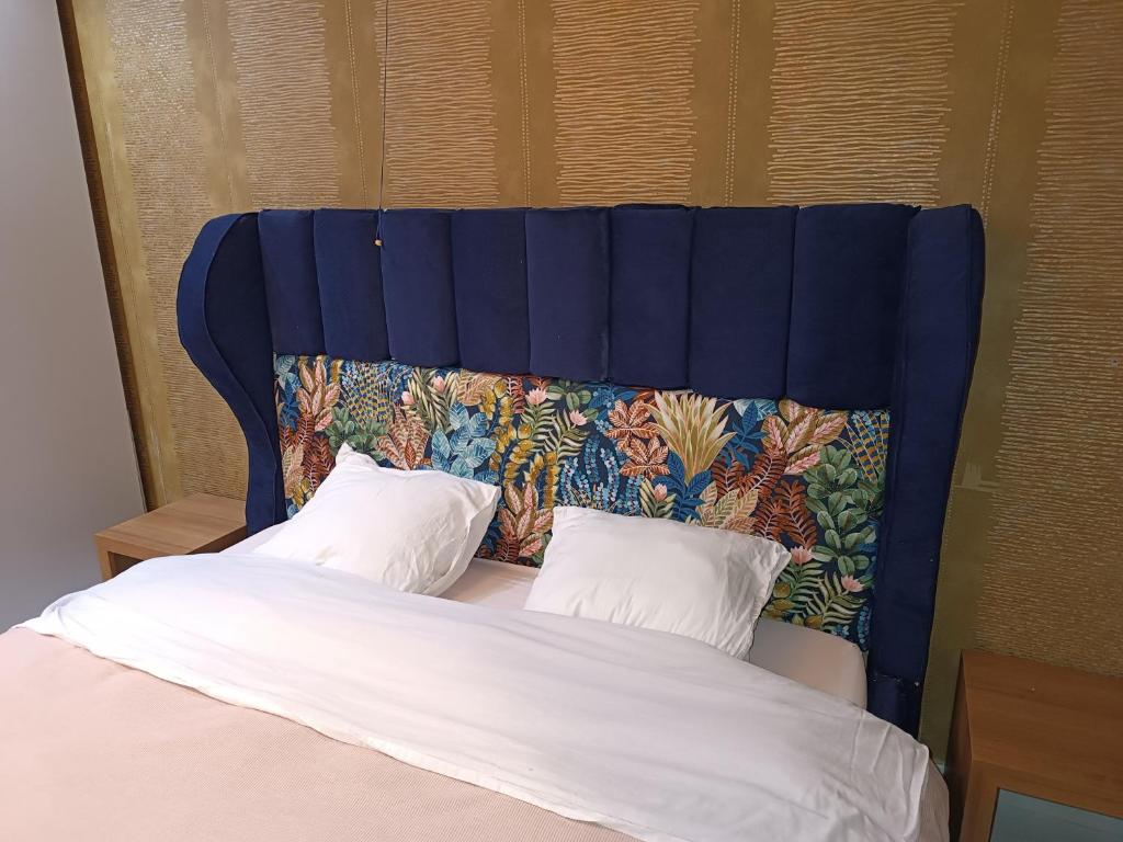 a bed with a blue head board with two pillows at Liège centre 13 Quai Godefroid Kurth POUR 2 PERS à 25 min gare Guillemins in Liège