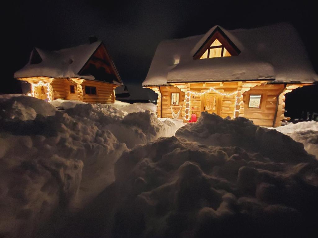 a log cabin covered in snow at night at DOMEK Z BALA ELITA in Kościelisko