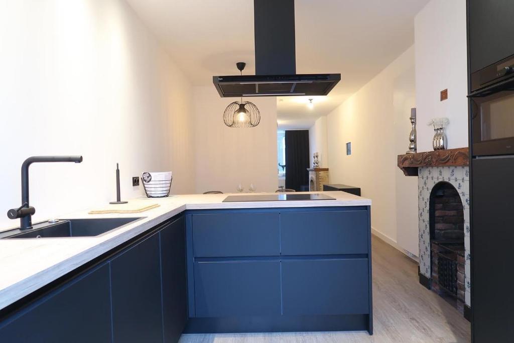 uma cozinha com armários azuis e uma lareira em sfeervol monumentaal pand em Maastricht
