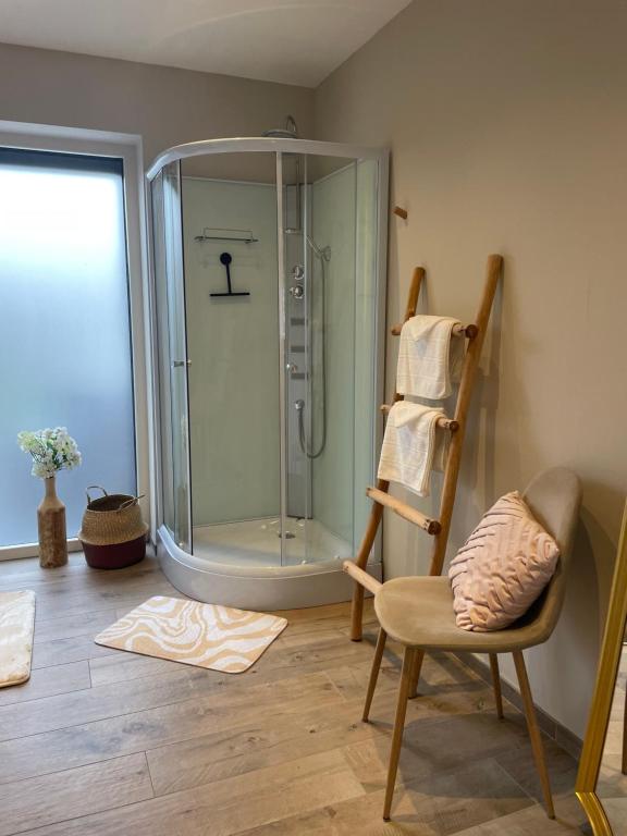 a bathroom with a glass shower and a chair at La petite halte in Godshuis