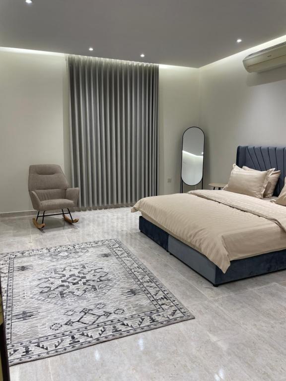 a bedroom with a bed and a chair and a rug at شقة غرفتين وصالة مدخل خاص باركنج سيارة in Riyadh Al Khabra