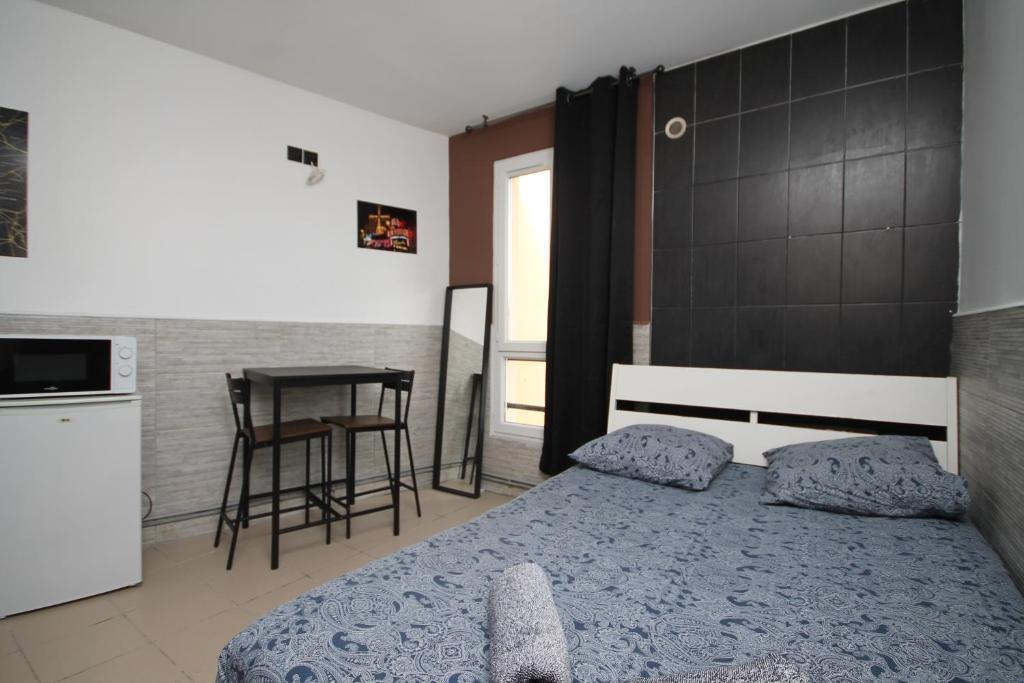 a bedroom with a bed and a kitchen and a table at 04 - Chambre avec lit double proche Paris et transports WIFI in Saint-Denis