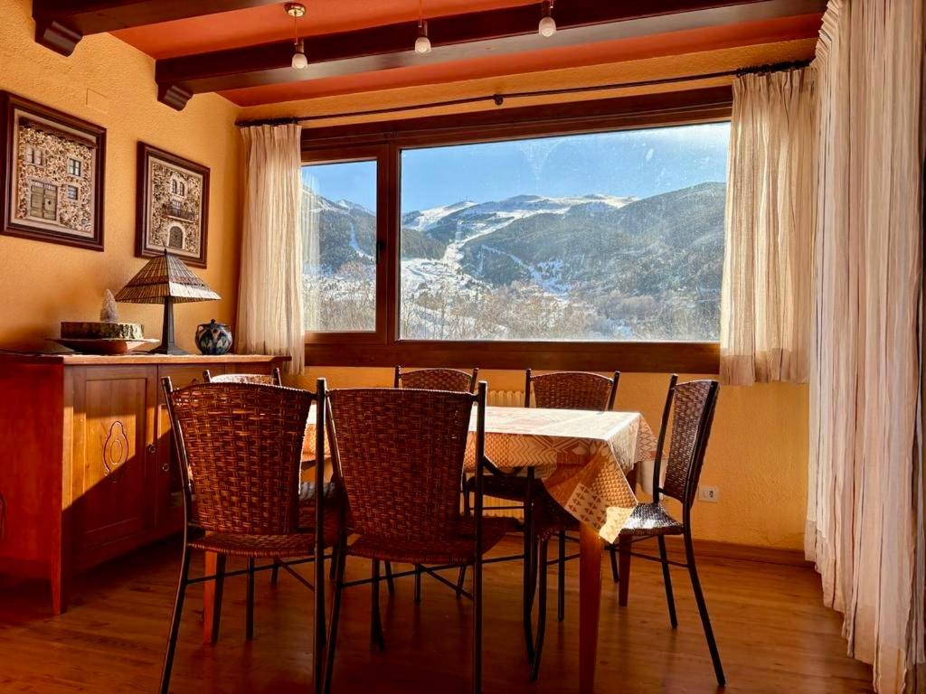 a dining room with a table and chairs and a large window at La casita de Cerler in Cerler